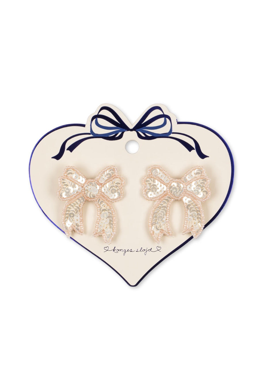 Heart-shaped card with sequin bow earrings on a white background