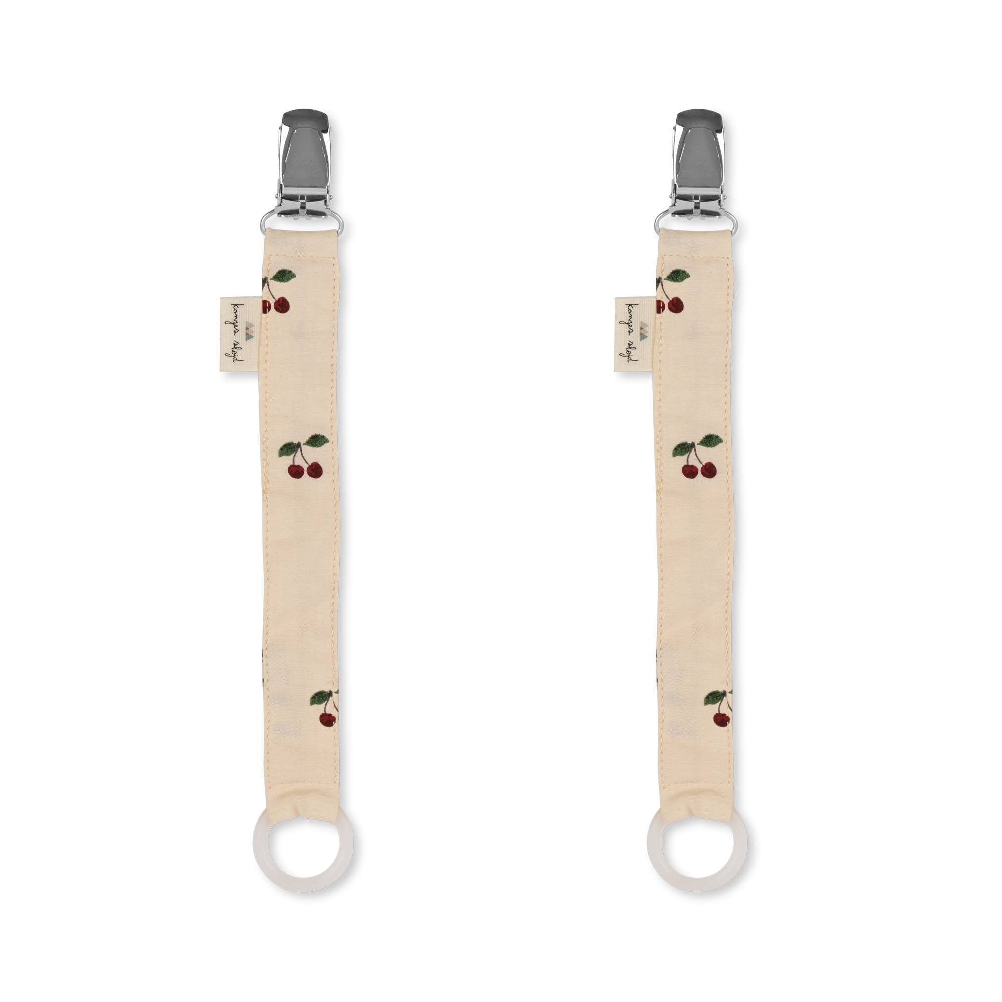 Two pacifier straps with cherry designs on a beige background, each strap has metal clips at the ends.