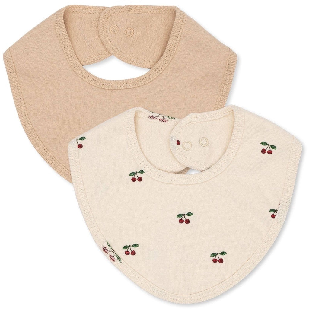 Two pack of beige baby bibs with a cherry design on one of them, displayed against a white background