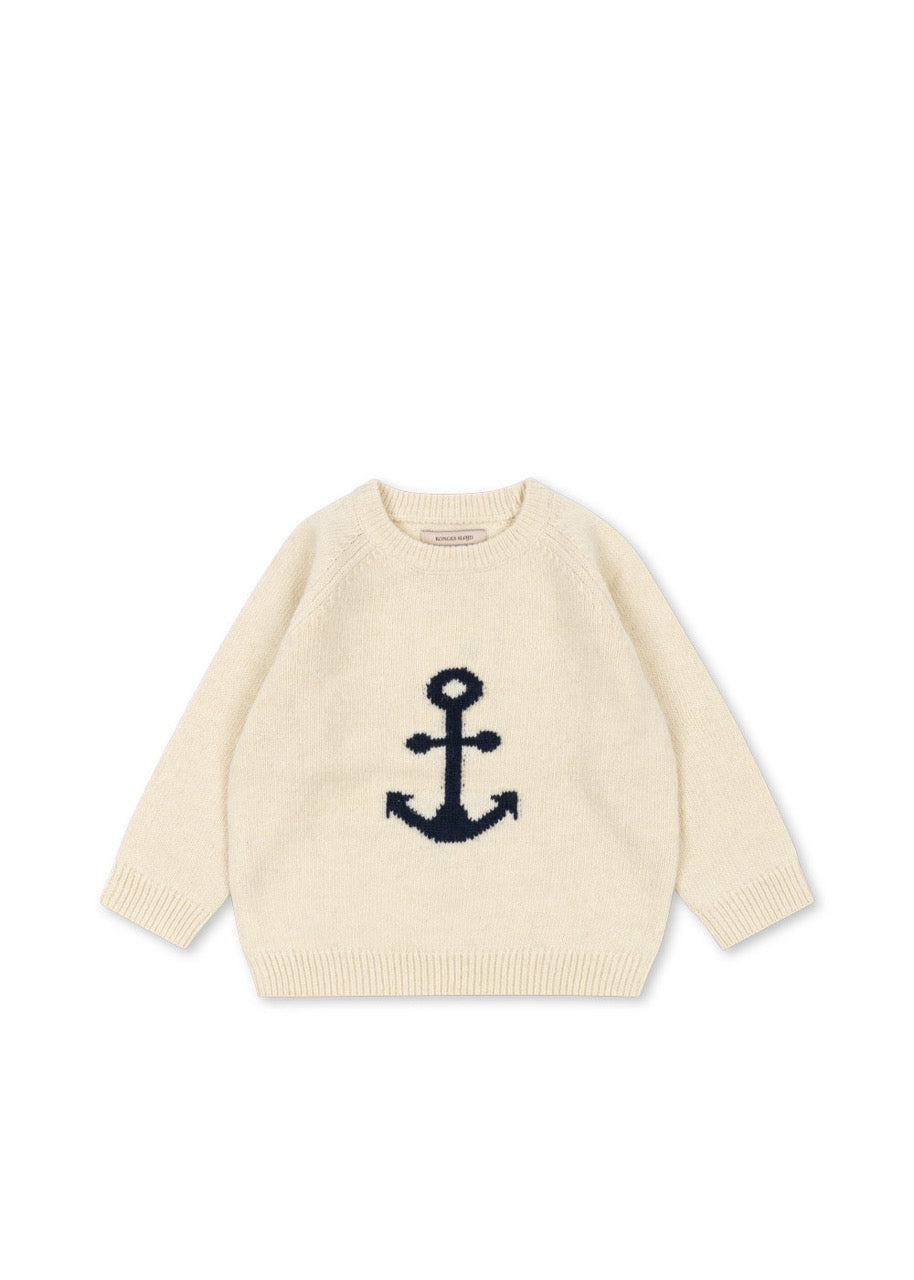 Beige sweater with a navy anchor design on a white background