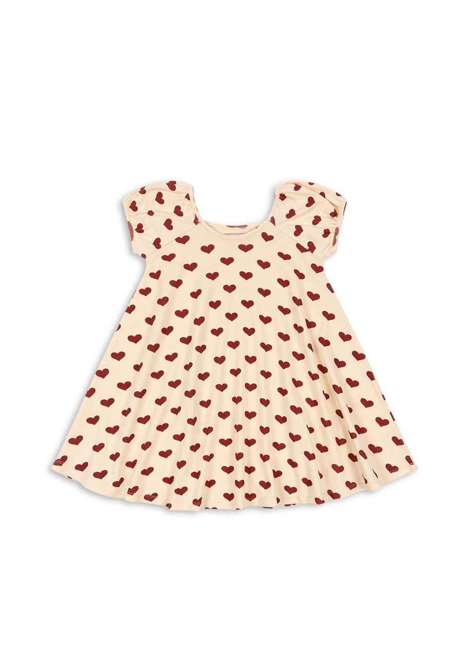 A short-sleeved beige dress with a red heart pattern.