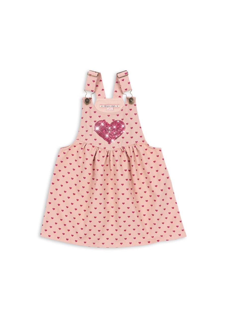 Pink polka dot pinafore dress with a heart design on a white background