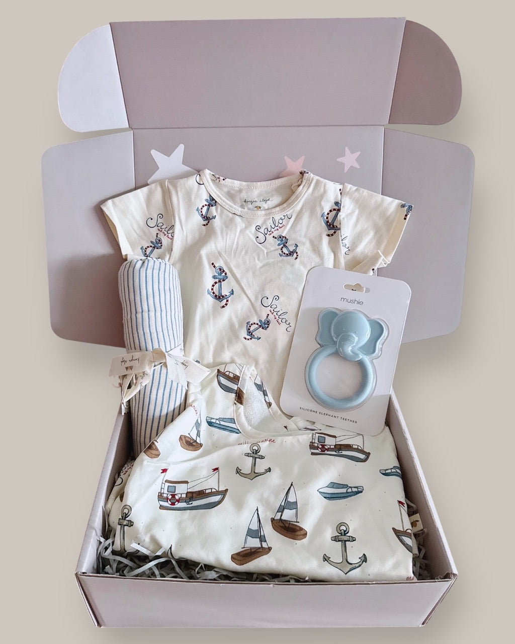 Baby clothing set with a shirt, pants, and teether in a box on a light background