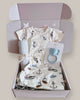 Baby clothing set with a shirt, pants, and teether in a box on a light background