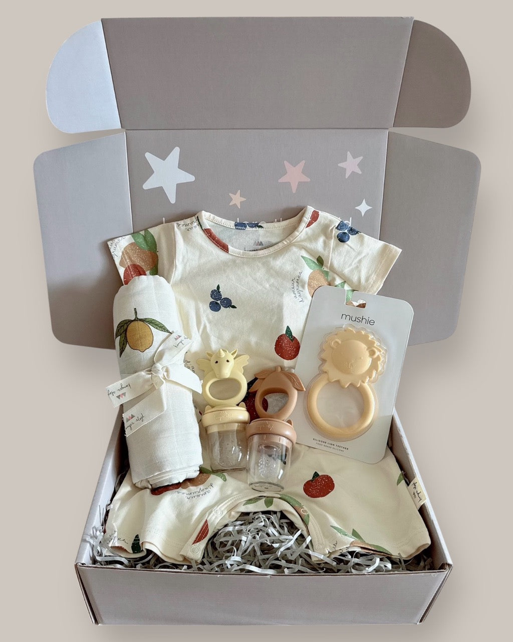 Baby gift set with clothes and toys in a box on a light background