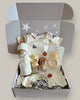 Baby gift set with clothes and toys in a box on a light background