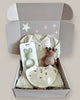 Baby gift set with clothing, teether, and plush toy in a box on a light background