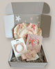 A gift box set for newborns that includes a Minnie-themed newborn body suit, a unicorn touch and feel book, a Bambi bonnet, and a cat teether, all displayed in a box with confetti and stars.
