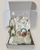 Baby gift set with clothing, bib, and toy in a box on a light background