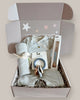 Baby gift set with striped outfit, blanket, and toys in a box on a light background