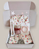 Baby gift set with baby clothes, a toy, and a headband in a box on a light background
