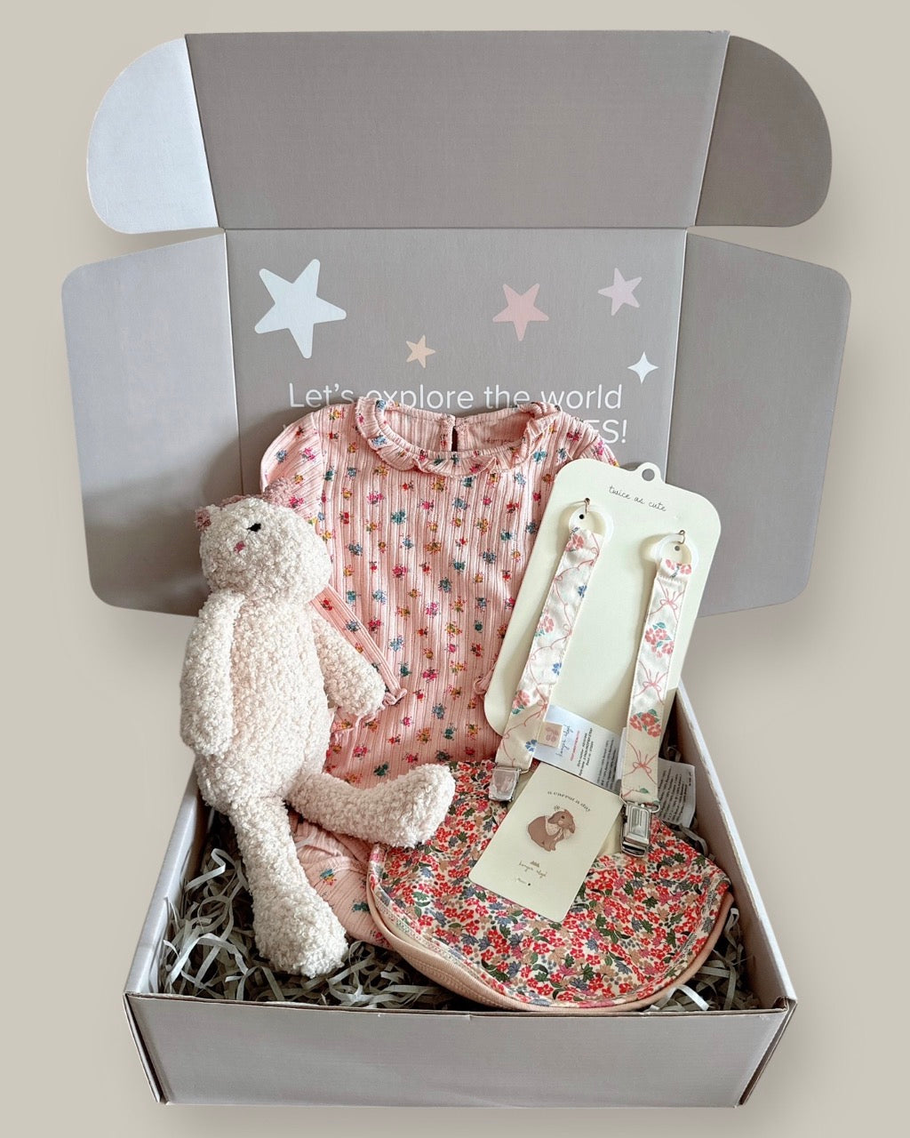 Baby gift set with clothes, teddy bear, and accessories in a box with a decorative label.
