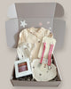 Baby gift set with clothes, hat, and shoes in a box on a light background