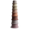 A set of eight stacked cups in varying shades of pink, beige, and gray, designed for young children.